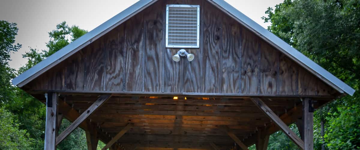 A wooden, covered bridge with green trees in the background.
