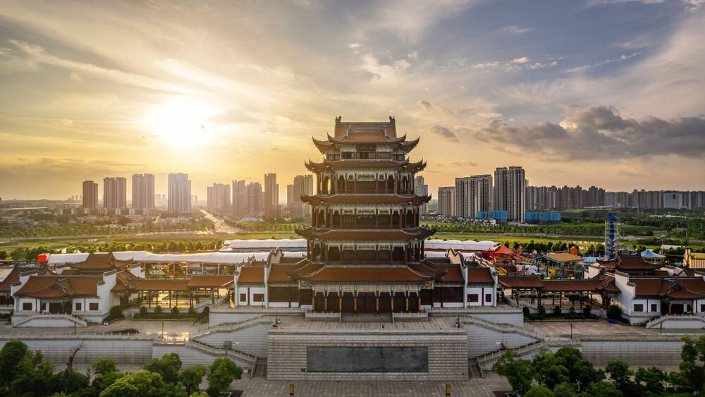 A traditional multi-tiered pagoda with a city skyline in the background.