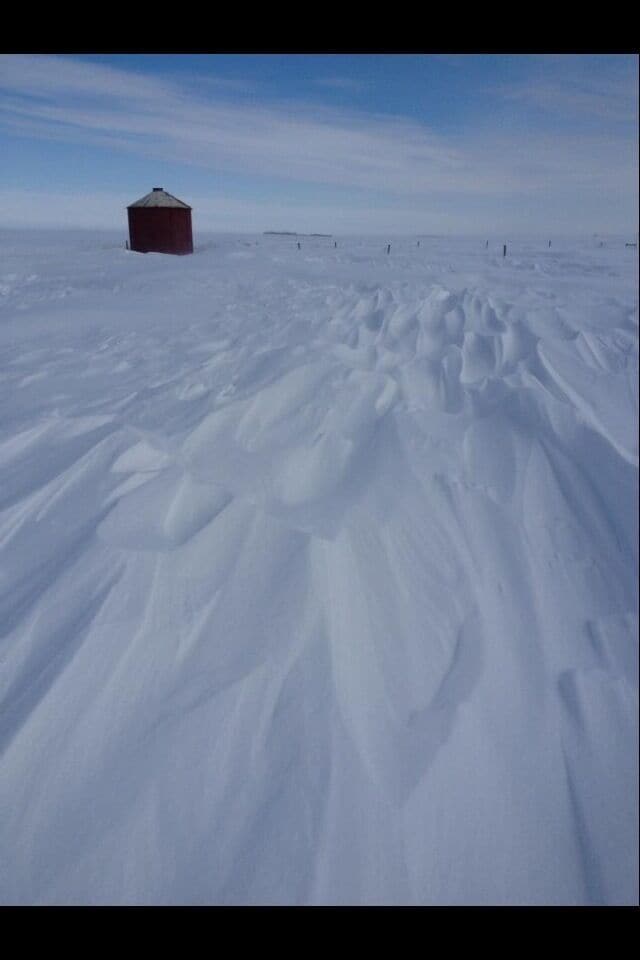 A snow-covered landscape with a red building in the distance.