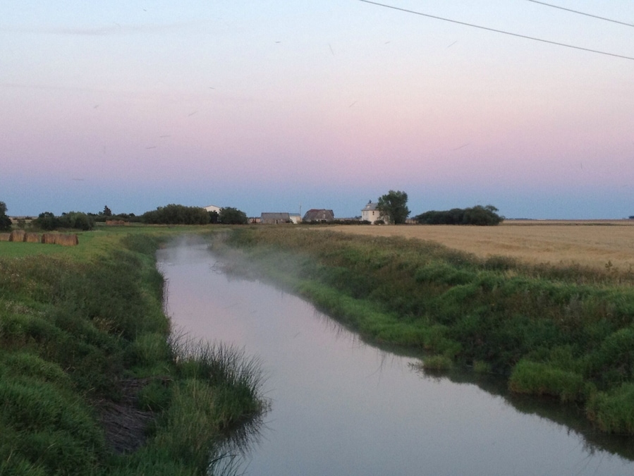 Mist on the creek that goes past a cute prairie farm house