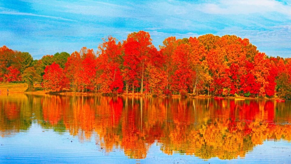 A lake with autumn-colored trees reflecting on the water.