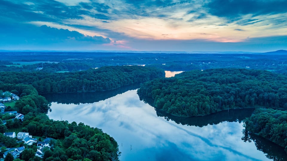 A river surrounded by dense forests and houses.