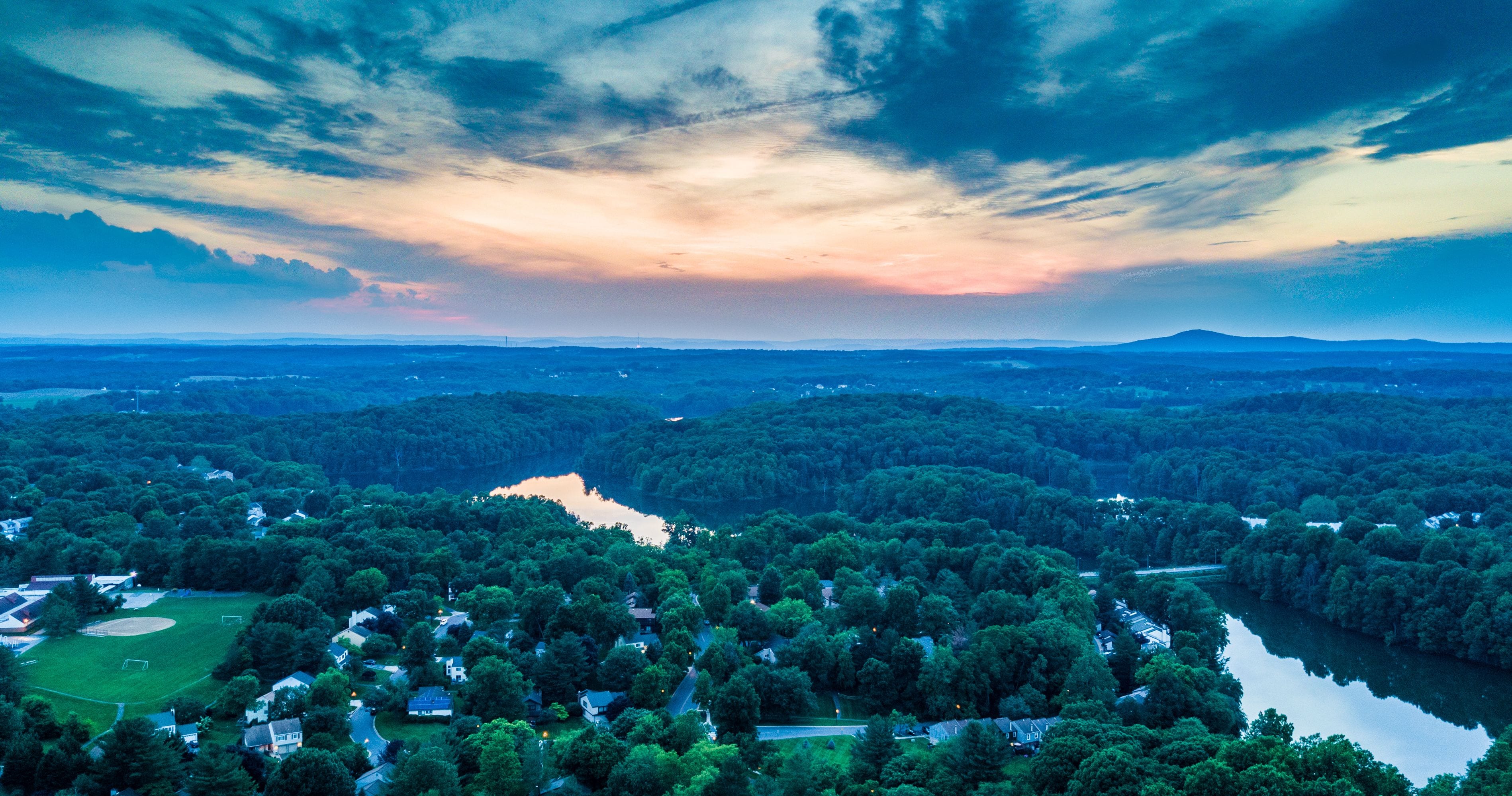 A river winding through a densely forested area with a backdrop of a dramatic sky.