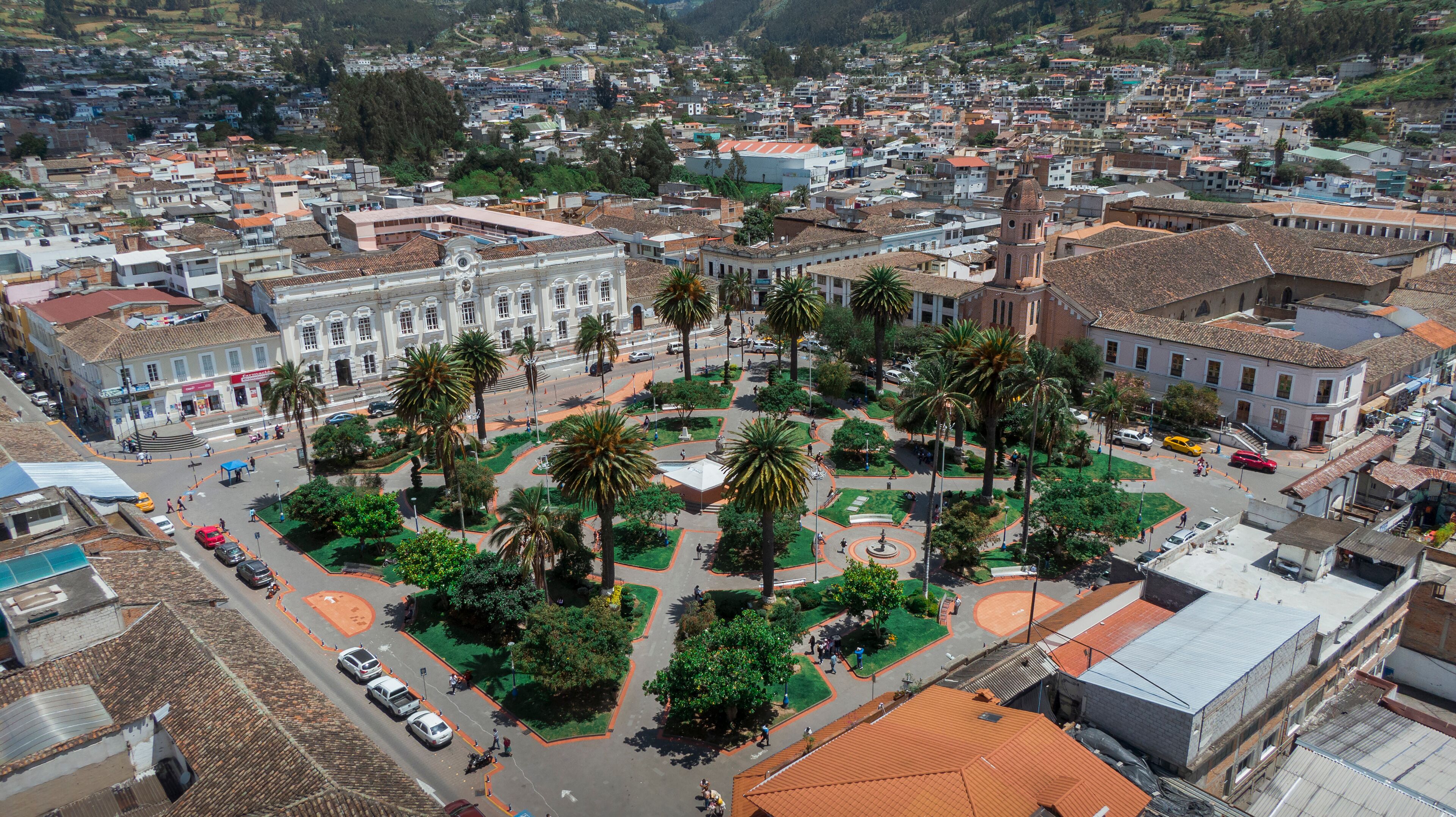A cityscape with a central plaza surrounded by palm trees and buildings.