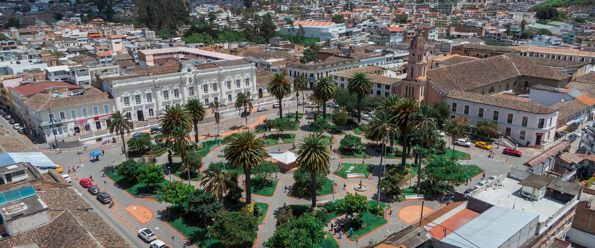 A cityscape with a central plaza surrounded by palm trees and buildings.