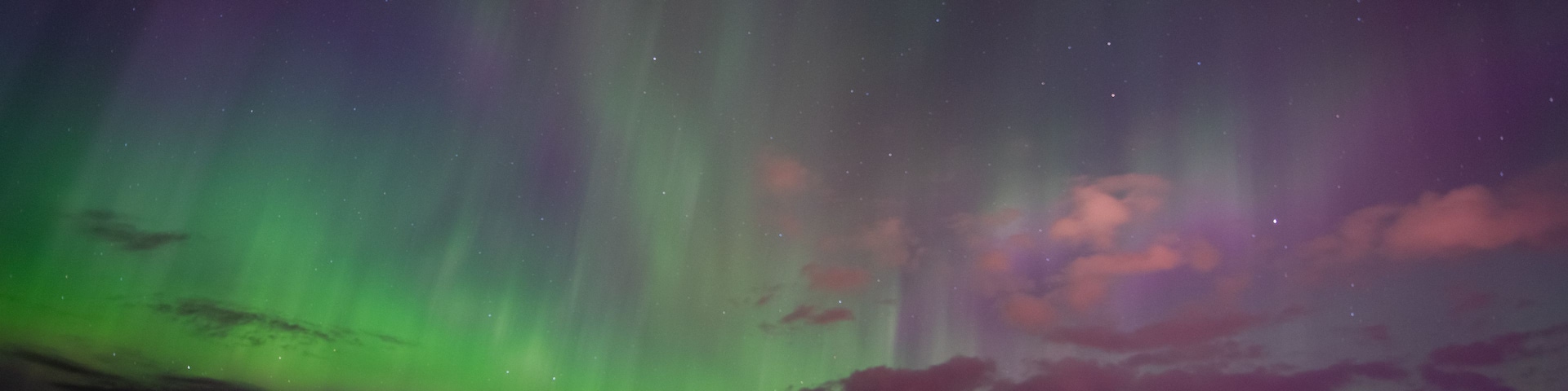 Auroras boreales sobre un pueblo a orillas de un lago, de noche.