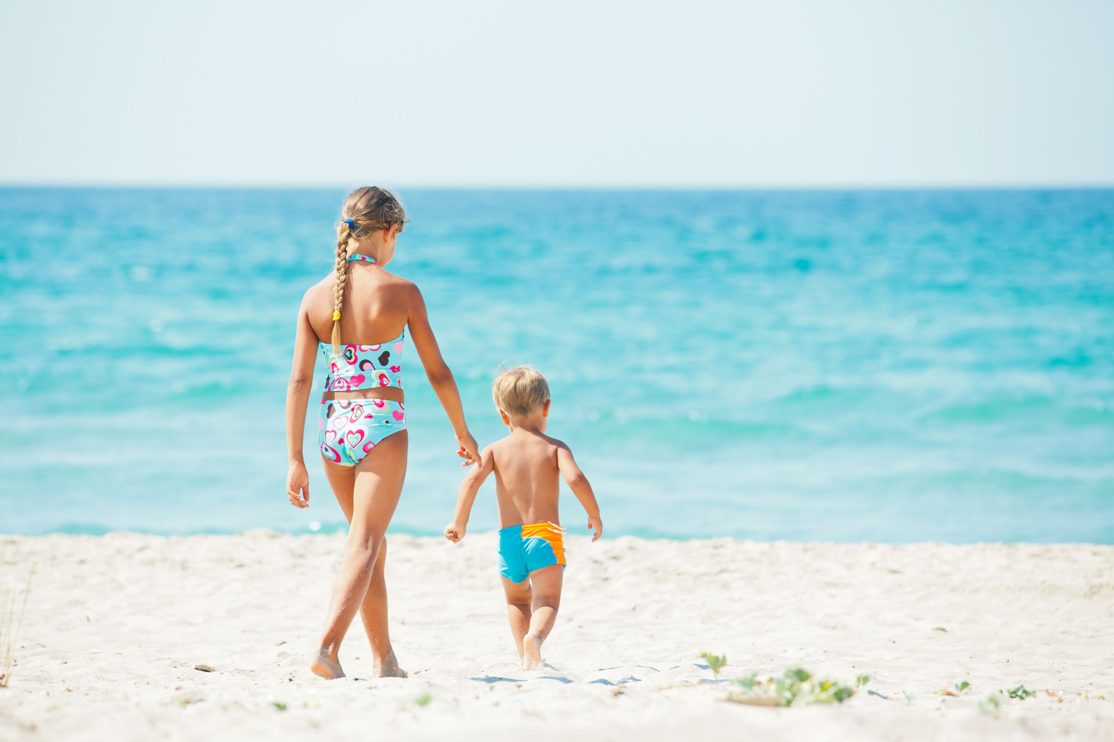 Young girl and boy playing happily at pretty beach