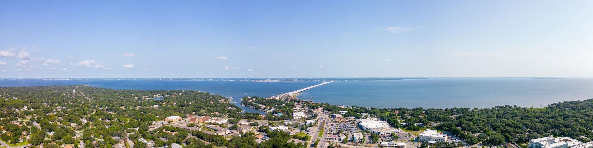 A coastal town with a marina, a long pier, and a baseball field.
