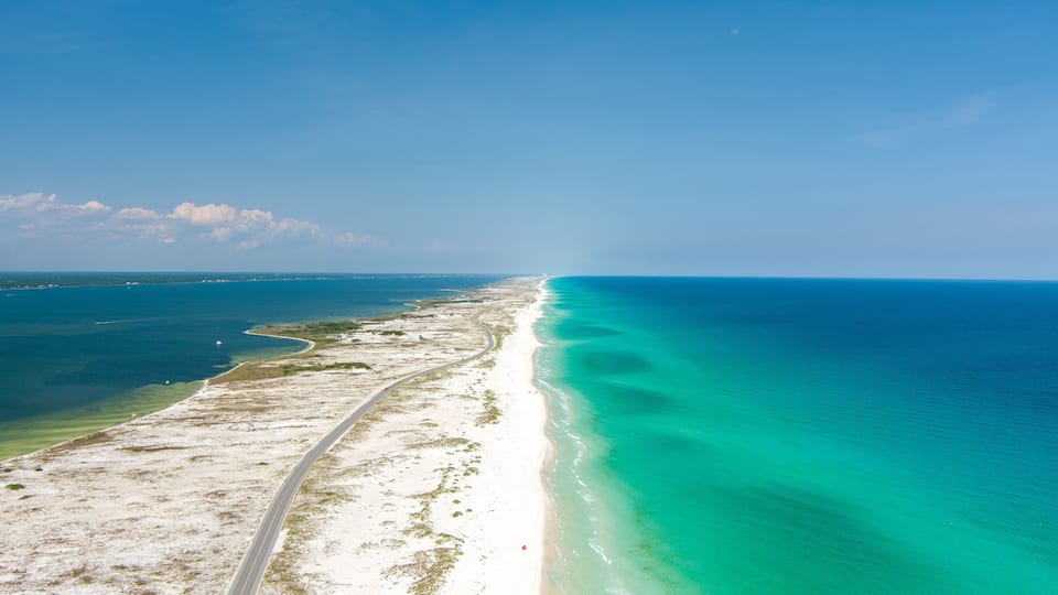 A coastal road with a beach and turquoise waters.