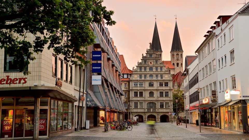 A cobblestone street with historic buildings, a church tower, and bicycles parked along the sidewalk.