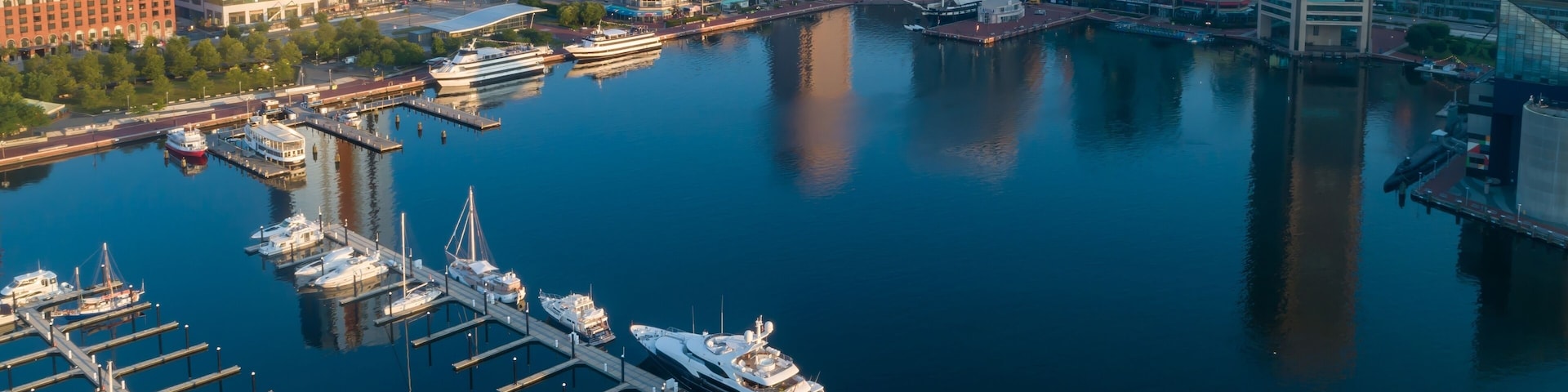 Una marina con yates amarrados, un horizonte urbano con edificios modernos y un río tranquilo que refleja las construcciones.