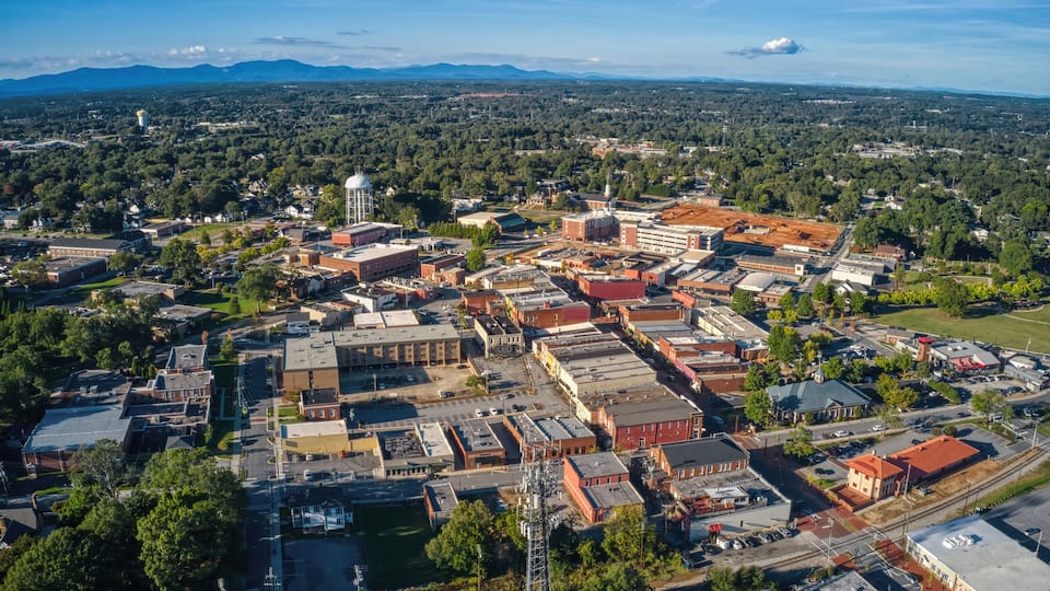 An aerial view of a town with a mix of historical and modern buildings, a prominent water tower, and a railway track.
