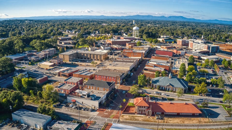An aerial view of a town with a prominent water tower, a train station, and a mix of commercial and residential buildings.