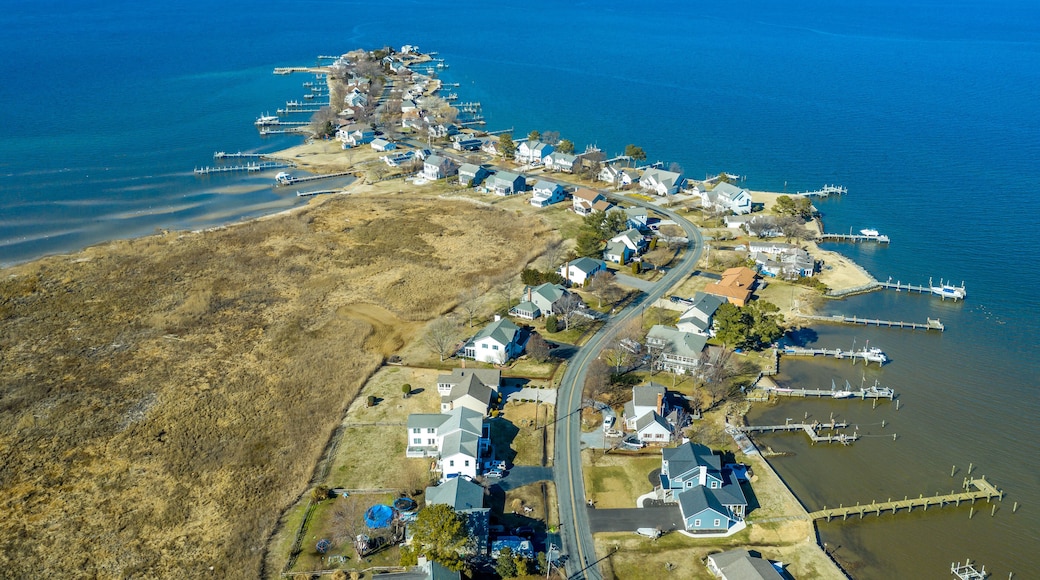 Aerial view of Kent Narrows peninsula inlet on Chesapeake in Grasonville Maryland, beach houses with private long docks for the sailboats line a road curving like an S shape with blue sky and water