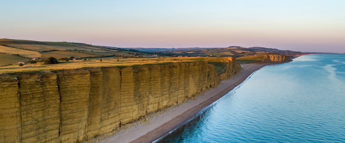 A coastal cliff with a beach and a calm sea.