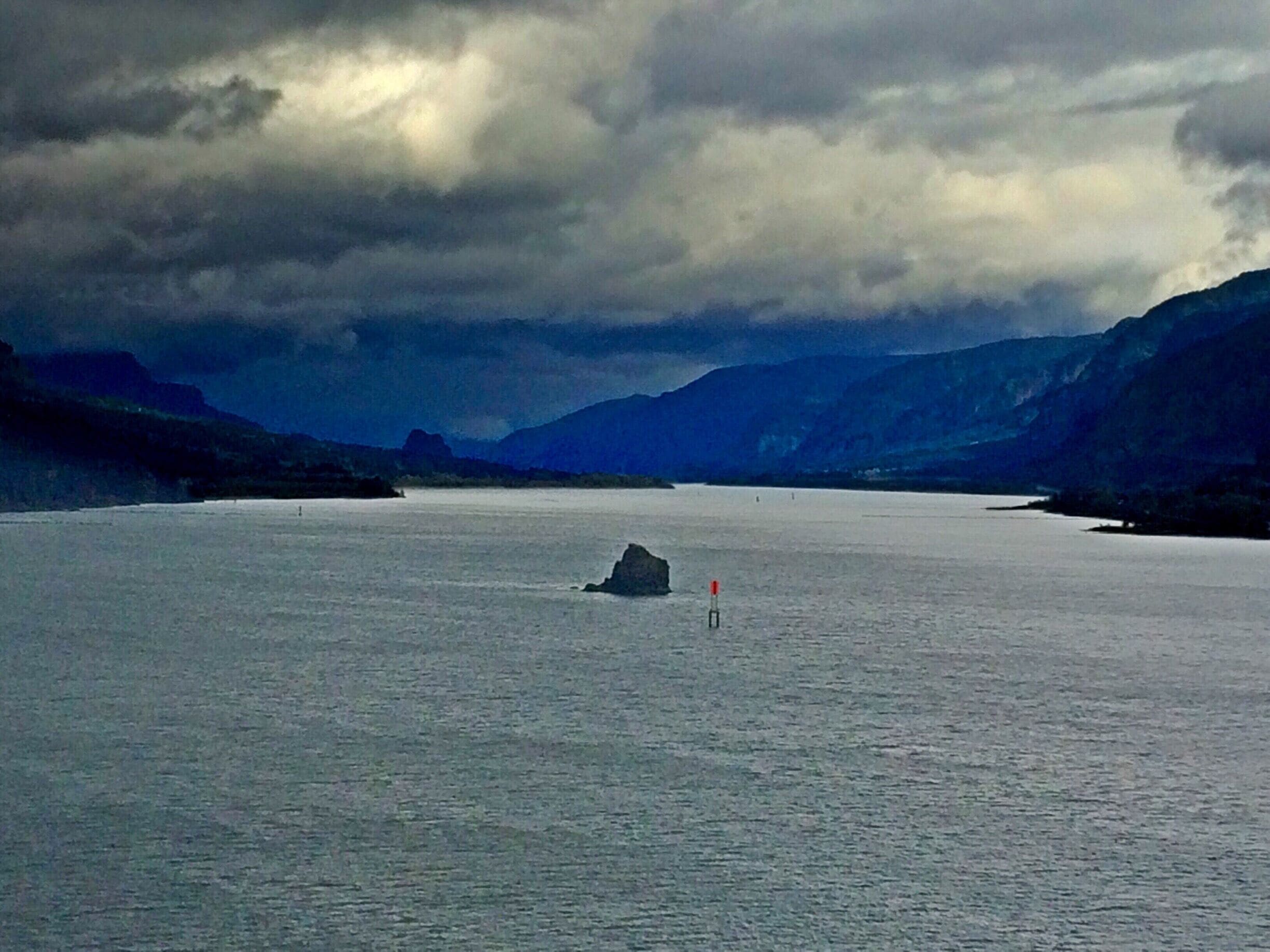 A large body of water with a small island and mountains in the background.
