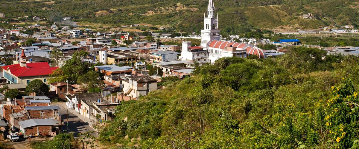 A town with a prominent church, surrounded by hills and greenery.