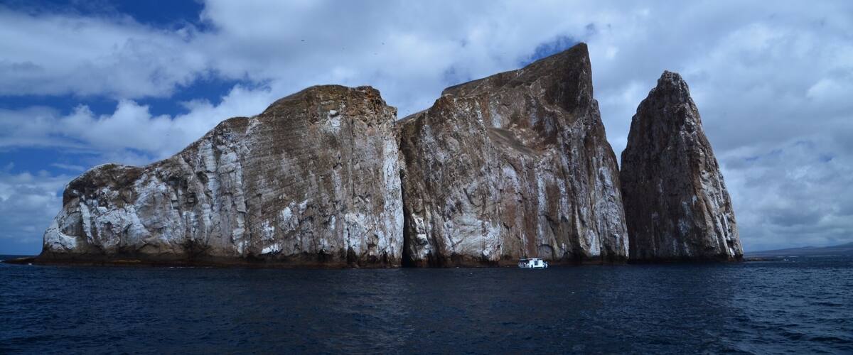 A large rock formation with a boat in the water.