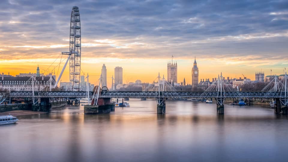A river with a bridge, a Ferris wheel, and the Big Ben clock tower.
