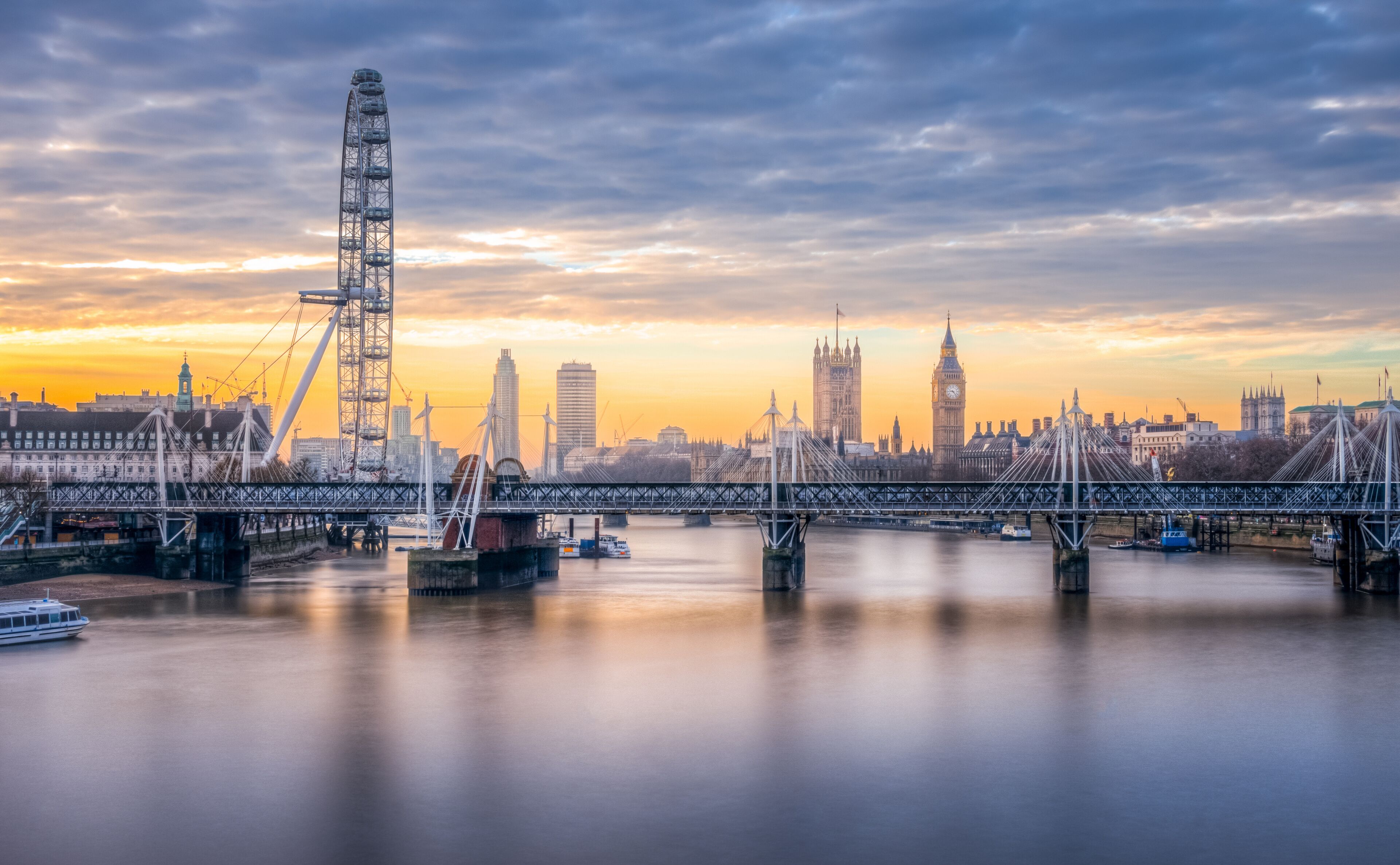 A river with a bridge, a Ferris wheel, and the Big Ben clock tower.