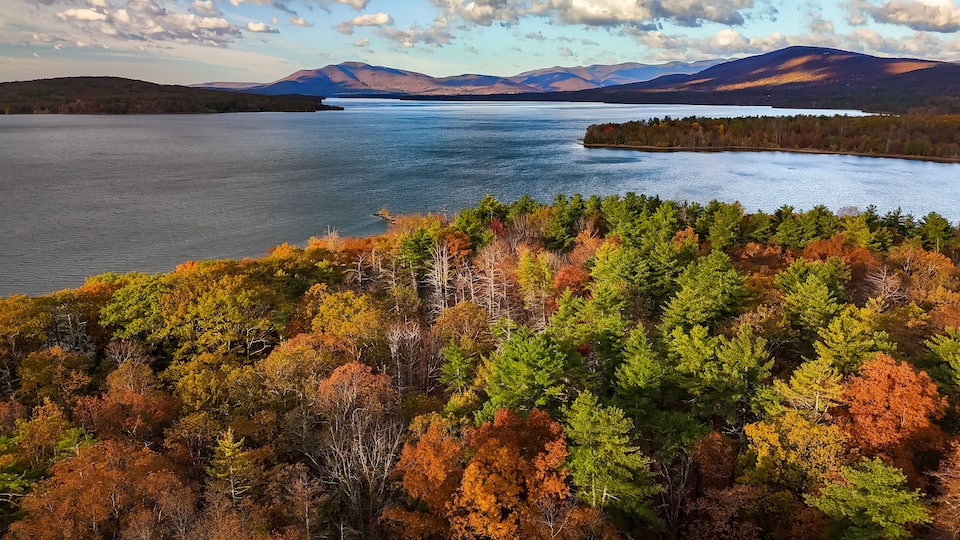 A lake surrounded by autumn-colored trees and distant mountains.