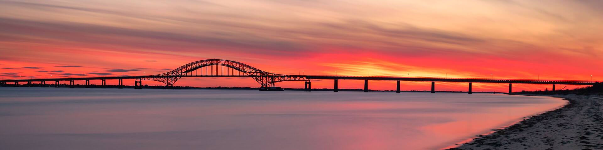 Smooth glassy water under steel tied arch bridge. Fire Island Inlet Bridge, Captree State Park New York