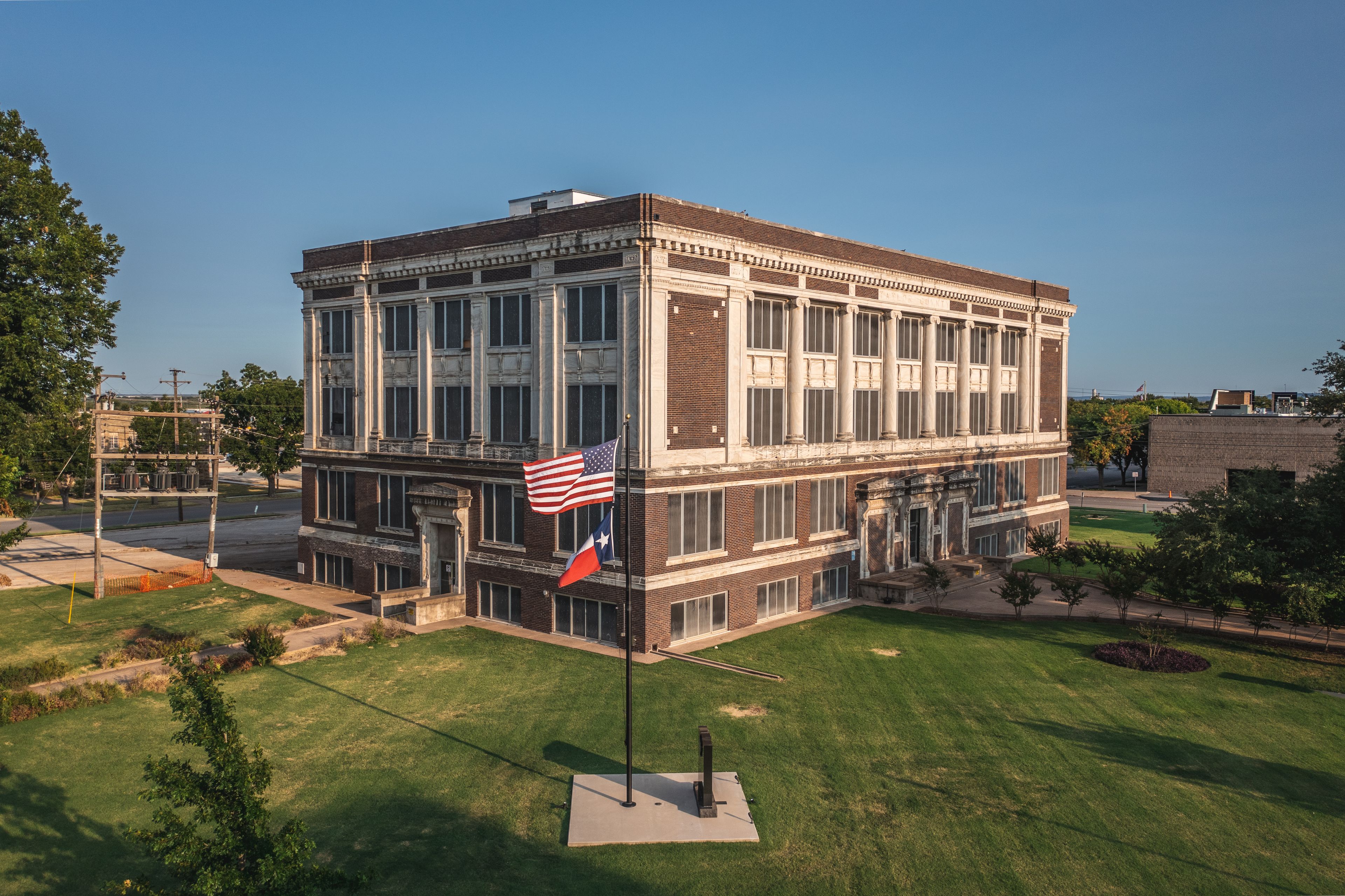 A historic building with a large American flag and a Texas state flag.