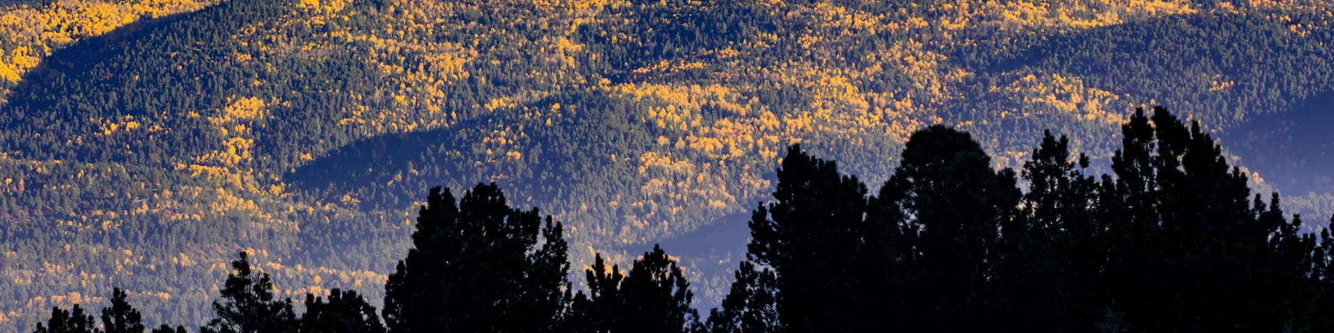 A mountainous landscape with autumn-colored trees and a clear sky.