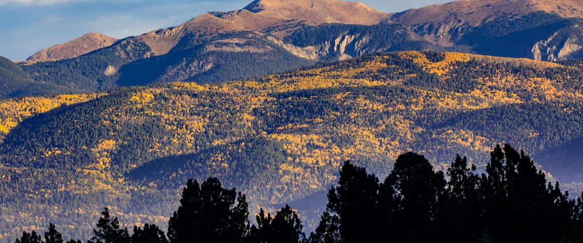 A mountainous landscape with autumn-colored trees and a clear sky.