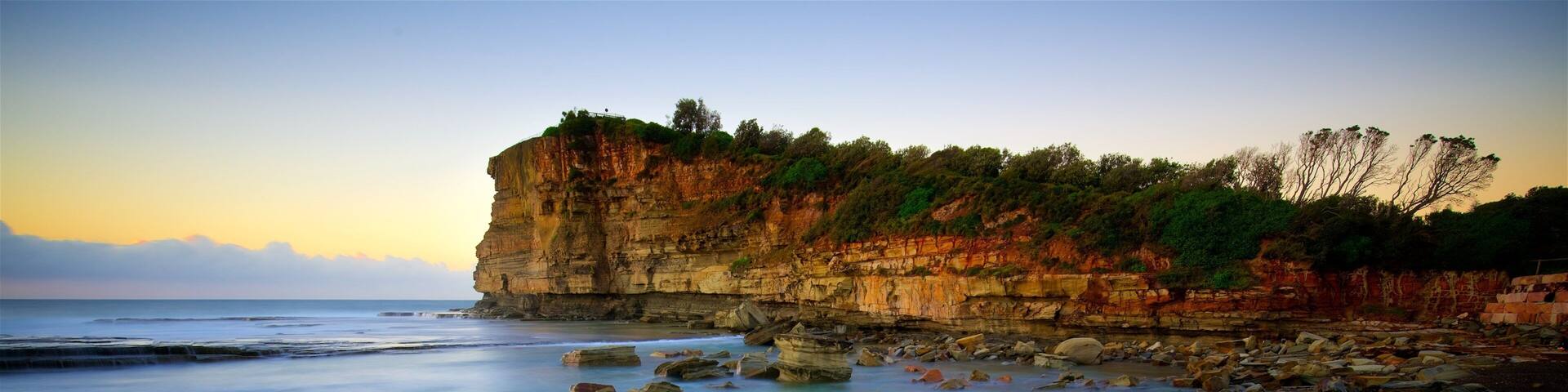 Terrigal featuring a bay or harbor, a sunset and rocky coastline