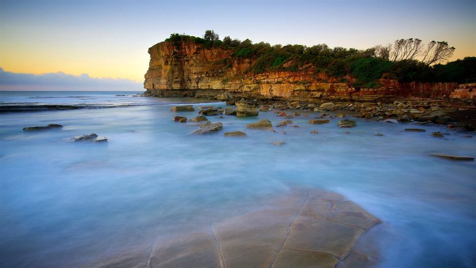 A coastal landscape with a rocky cliff and calm sea.