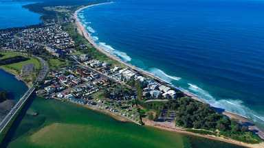 An aerial view of a coastal residential area with a beach, a bridge, and a marina.
