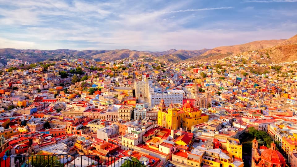 A densely packed cityscape with a prominent yellow church and surrounding colorful buildings.