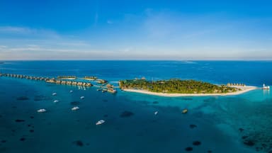 Panoramic aerial view of a luxury resort with boats anchored along the coast on Raa Atoll in the Laccadive Sea, Maldives archipelagos.