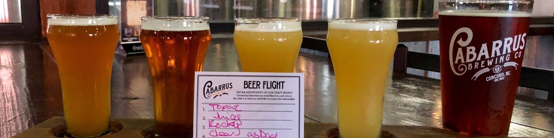 A beer flight display at a bar with four different beers and a sign for a 'Beer Flight' offering.