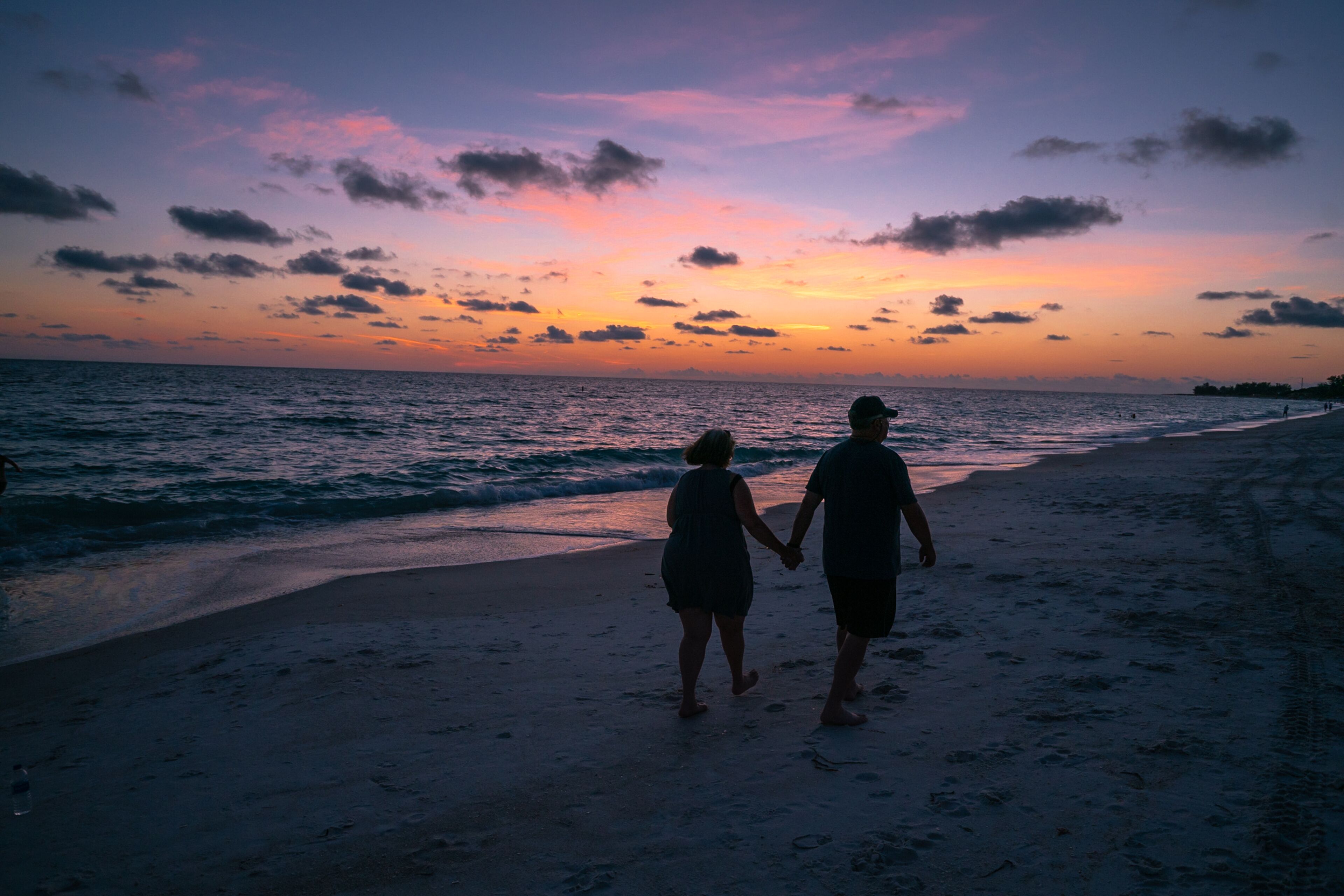 A couple walking under sunset beautiful sky at Anna Maria Beach Beadeton Florida
