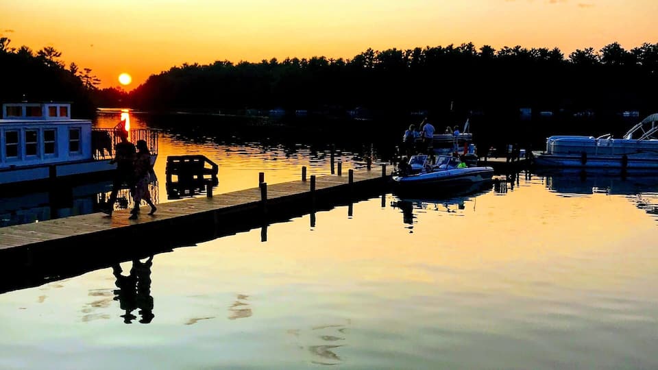 A sunset over a calm lake with boats docked along the shore.