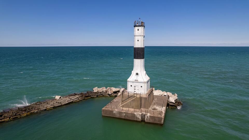 A lighthouse on a concrete base surrounded by water.