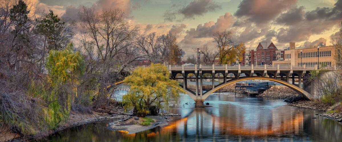 A river with a bridge, trees, and a building in the background.