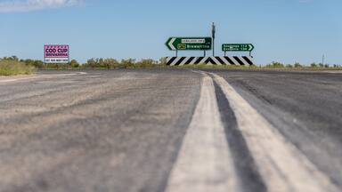 Low angled view of a line down the centre of an outback road leading to a traffic sign