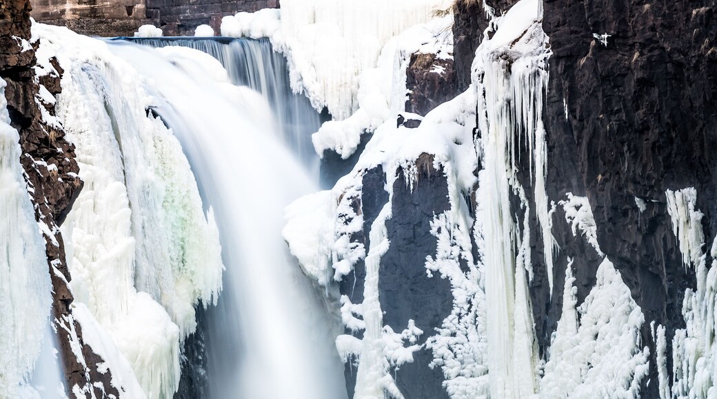A frozen waterfall surrounded by snow-covered rocks and ice formations.