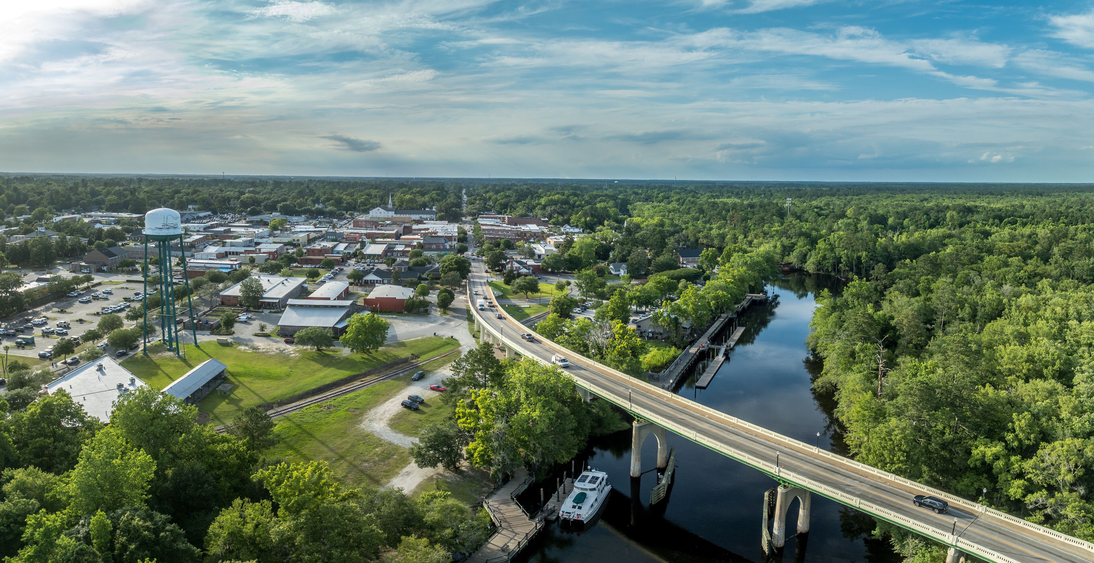 A river running through a town with a bridge, surrounded by dense greenery.
