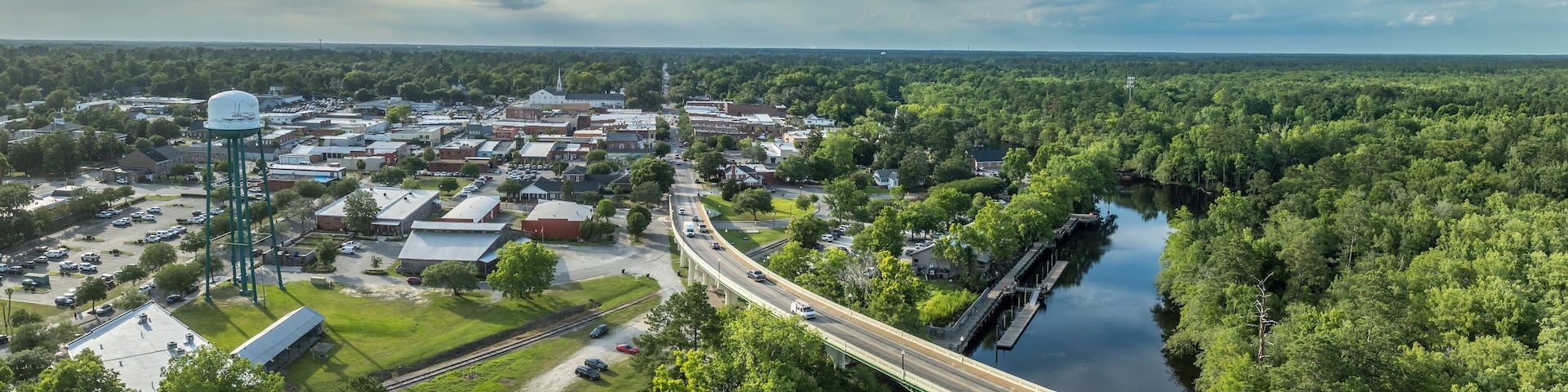 A river running through a town with a bridge, surrounded by dense greenery.