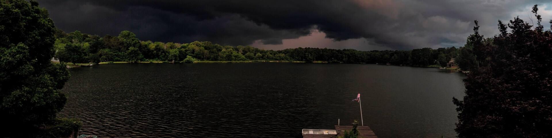 A lake surrounded by trees under a stormy sky.