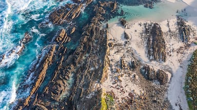 A coastal landscape with rocky cliffs, clear turquoise waters, and sandy beaches.