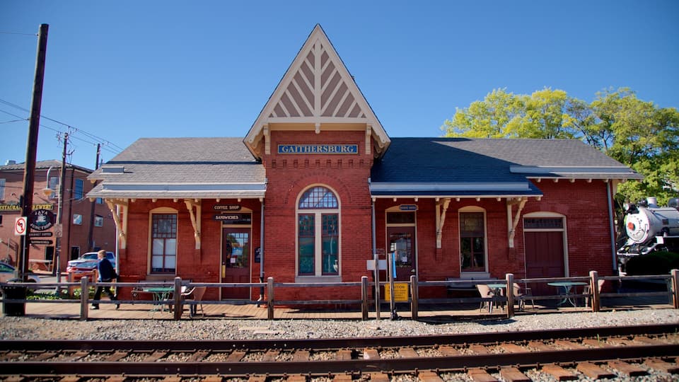A red brick train station with a sign reading "Gaithersburg" and a steam locomotive in the background.