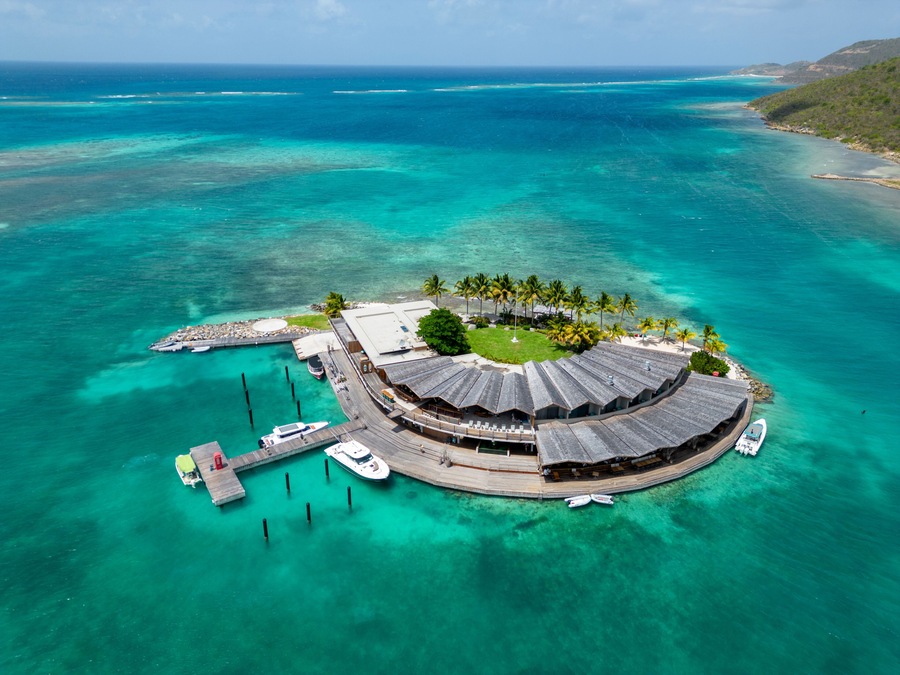 Una isla tropical con una edificación circular rodeada de palmeras y aguas turquesas cristalinas.