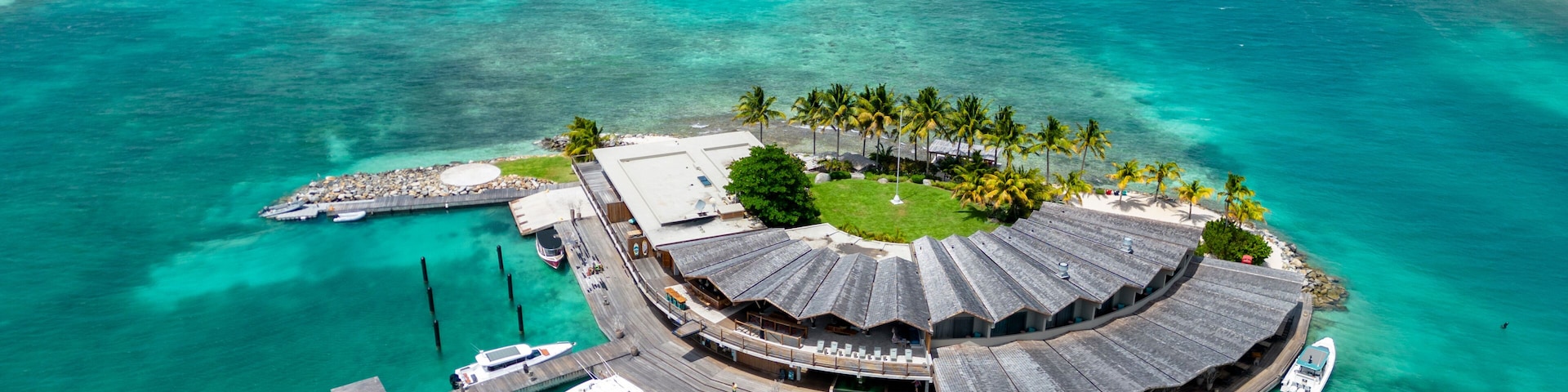 Una isla tropical con una edificación circular rodeada de palmeras y aguas turquesas cristalinas.