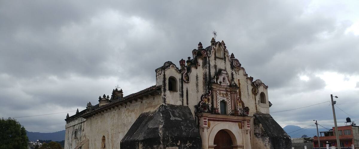 An old church with a steep, ornate roof and a large arched entrance.