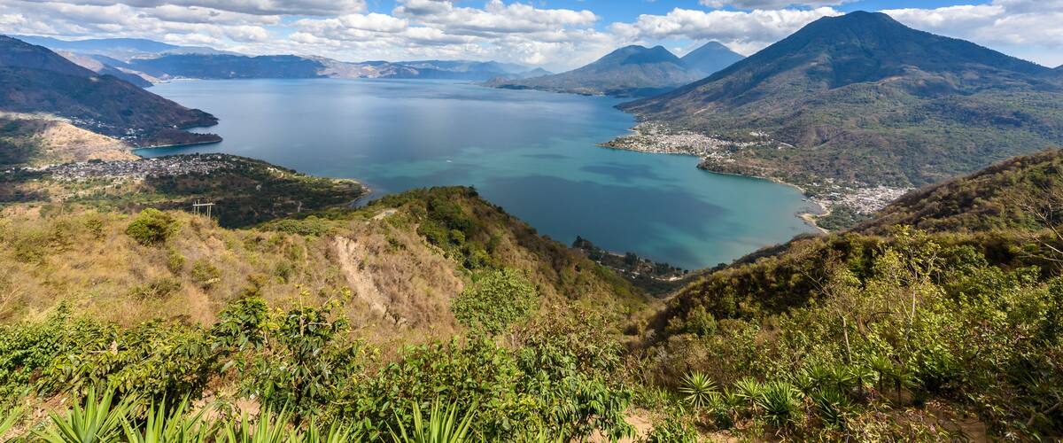 A coastal landscape with a large body of water, mountains, and a small town.